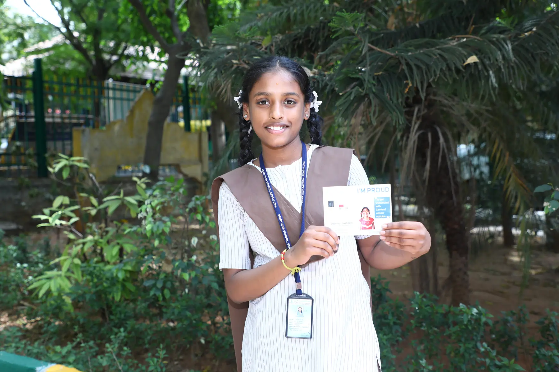 A vaccinated student proudly holding her vaccination card
